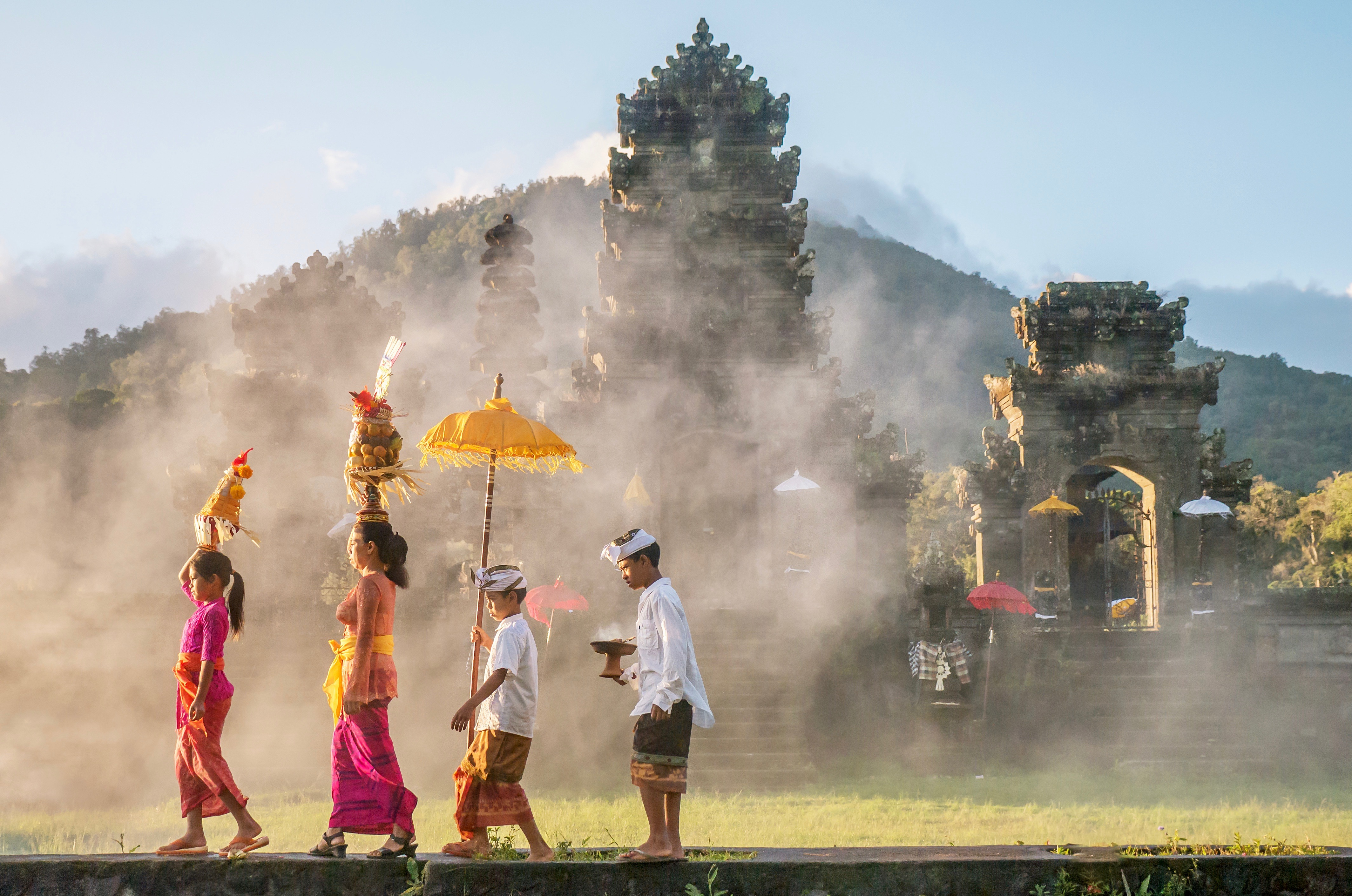 shutterstock_1053593438 Ubud, Bali - July 30, 2016. Illustrative Editorial. Showing traditional Balinese male and female ceremonial clothing and religious offerings, as a mother and children walk to a Hindu.jpg