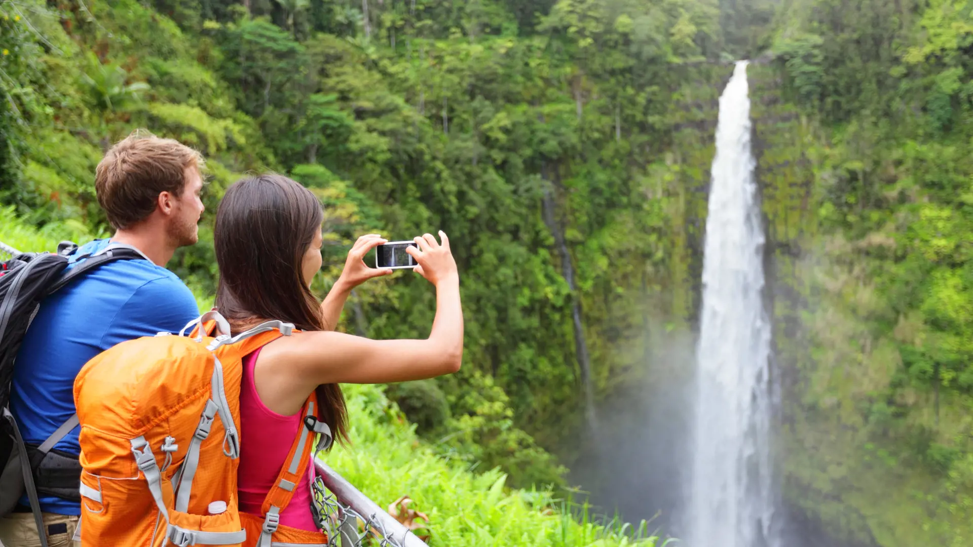 Couple tourists on Hawaii by waterfall. Tourist taking photo pictures of Akaka Falls waterfall on Hawaii, Big Island.jpg