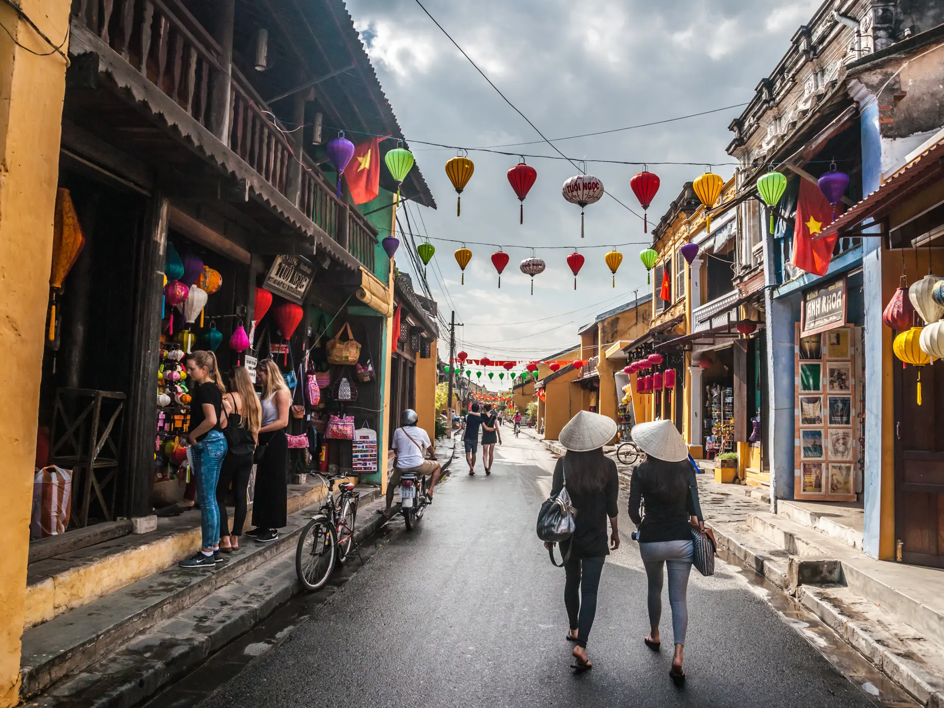 HOI AN, VIET NAM Two unidentified asian female tourists in traditional vietnamese conical hats walk.jpg