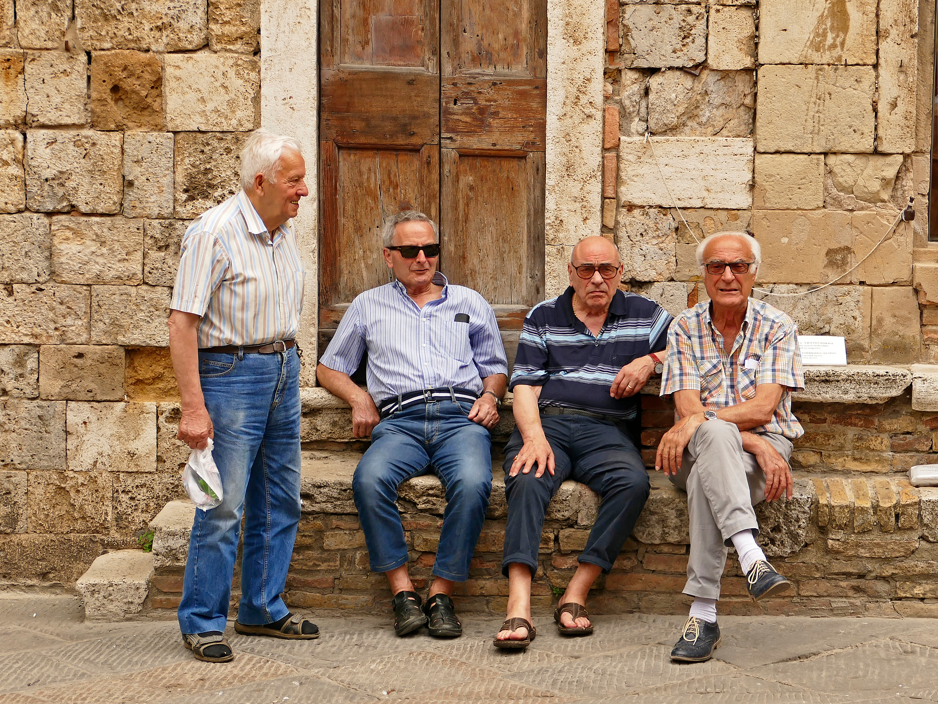 Gamle venner får en sludder på en torveplads i San Gimignano