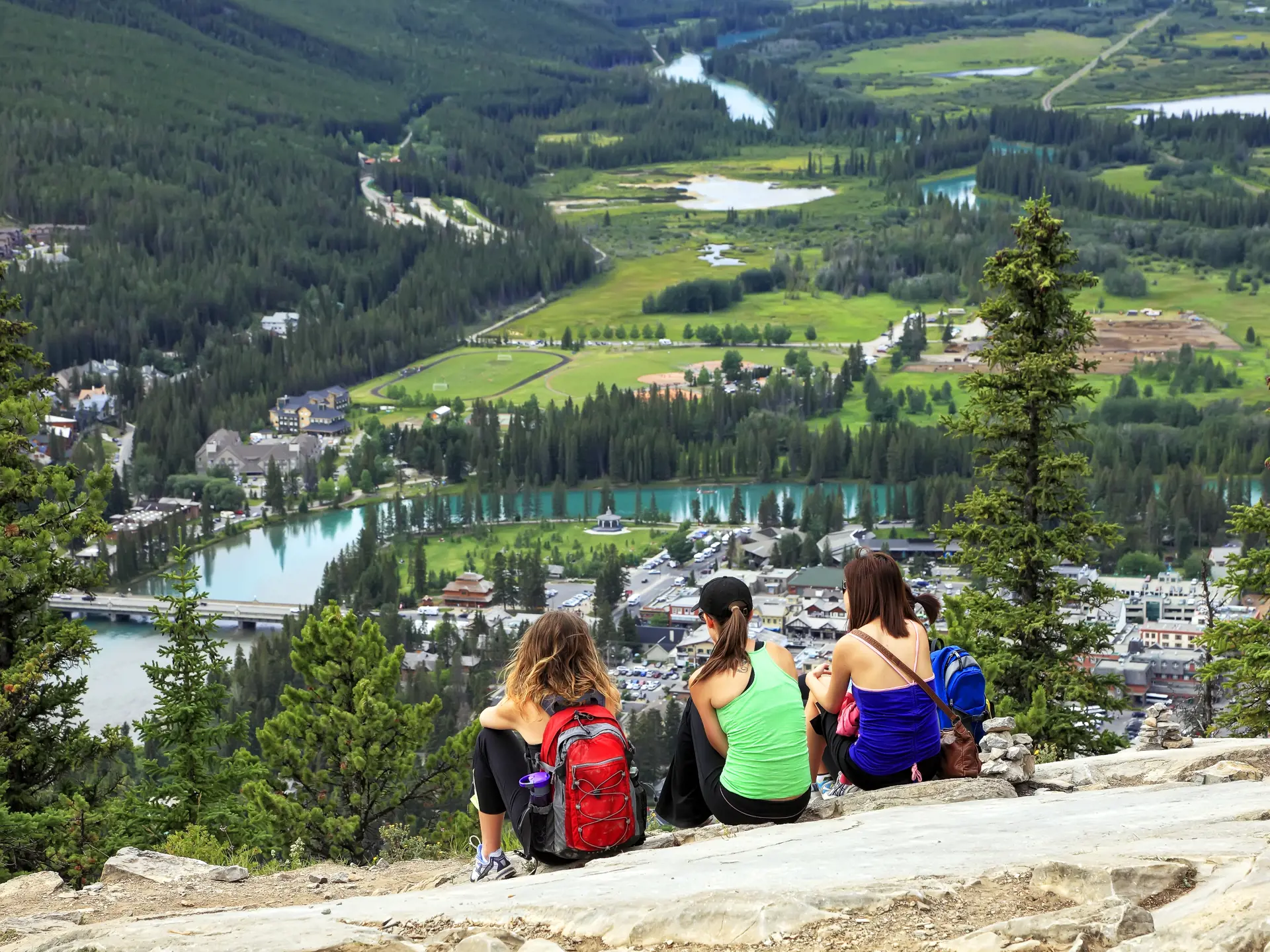shutterstock_83229271 ourists sitting on a grief and looking at a panorama of a small town Banff in a Bow river valley (Banff NP).jpg