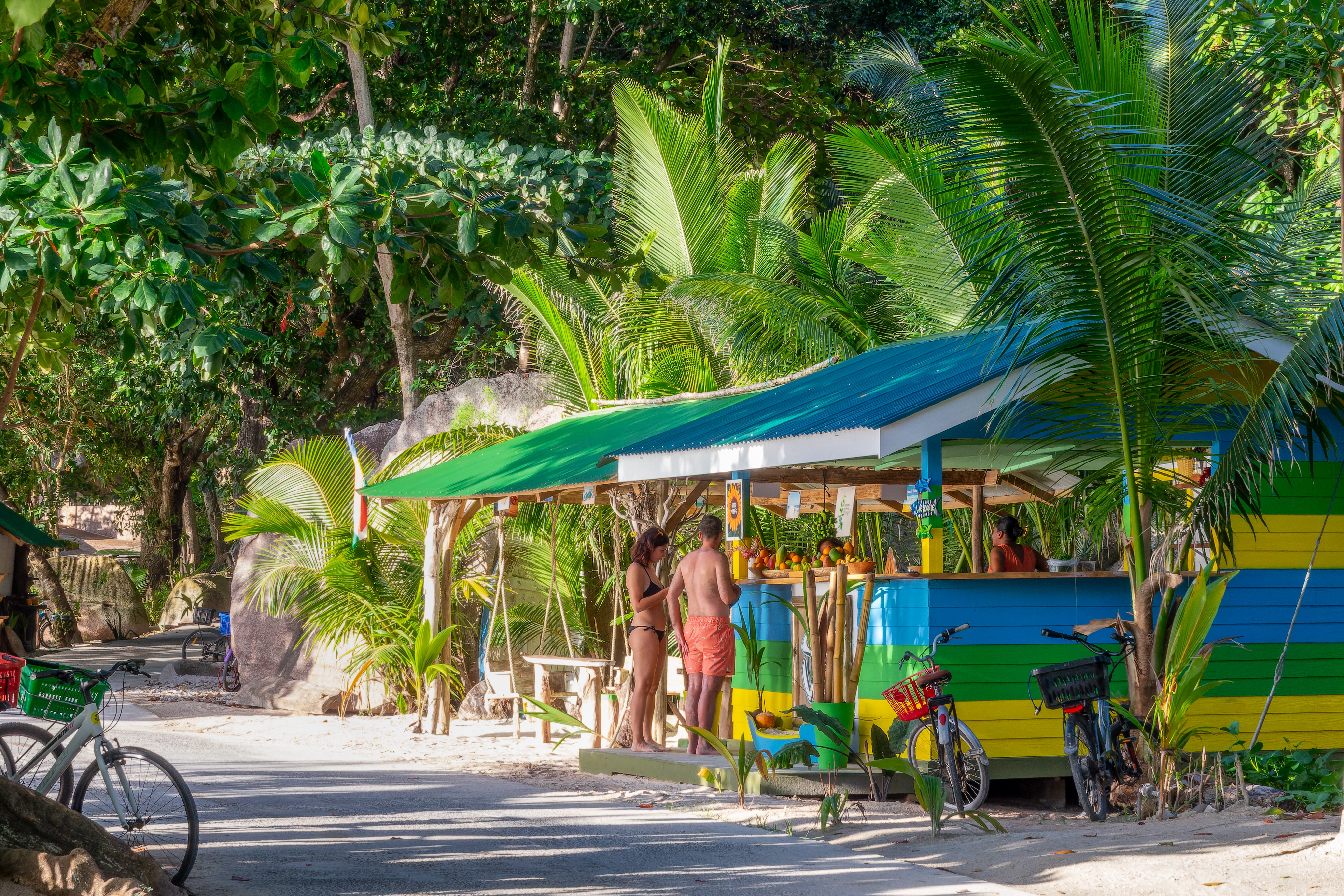 Shutterstock 2452608153 Tourists And Bikes At A Beach Bar On The Road Of La Digue Island